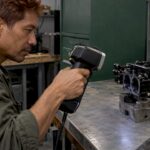 Technician scanning a polished black carburetor body